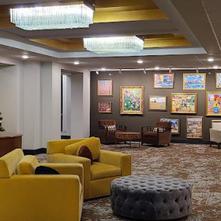 A cozy lounge area featuring modern yellow seating, artistic wall decor, and elegant lighting.