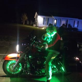 A festive rider on a motorcycle adorned with glowing green lights, celebrating the holiday spirit.