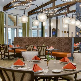 An elegant restaurant dining area with neatly set tables and decorative chandeliers.