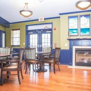 A bright dining room with tables, chairs, and a fireplace.