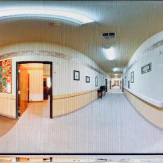 A panoramic view of an interior hallway featuring doors and framed artwork on the walls.