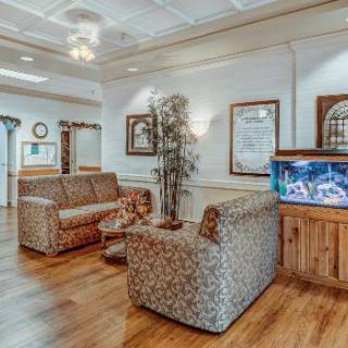 A cozy waiting room featuring patterned sofas, an aquarium, and wooden flooring.