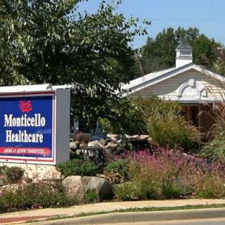 A healthcare facility sign in front of a landscaped building with trees and plants.