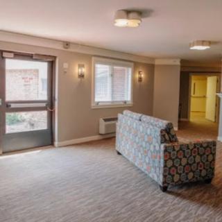 A spacious lobby area featuring a patterned sofa, carpet flooring, and ample lighting.