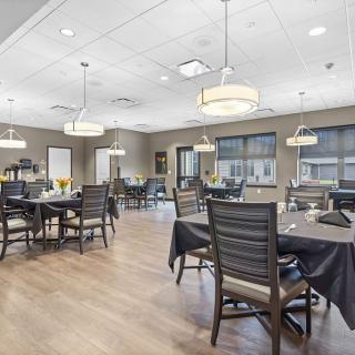 A modern dining room with neatly arranged tables and chairs, featuring contemporary lighting.