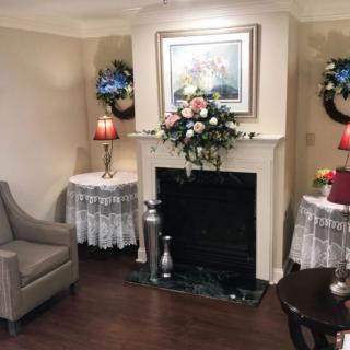 A cozy living room with a decorated fireplace, flowers, and elegant furnishings.