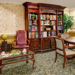 A cozy library room with a large bookshelf, comfortable seating, and elegant decor.