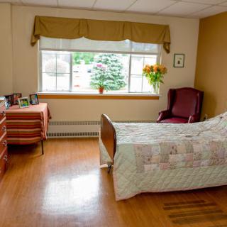 A cozy and well-lit bedroom featuring a comfortable bed, an armchair, and warm decor.