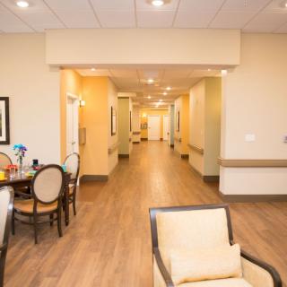 A well-lit hallway with chairs and a table, featuring warm decor.