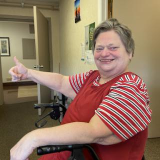 A cheerful woman in a wheelchair giving a thumbs up, showcasing positivity and joy.