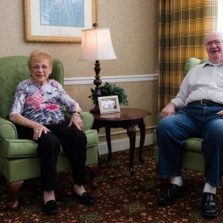An elderly couple sitting comfortably in a living room setting.