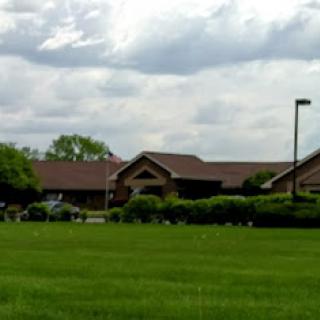 A serene view of a building surrounded by lush green grass under a partly cloudy sky.