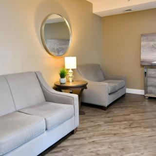 A modern living room with gray sofas, a mirror, and a lamp on a side table.