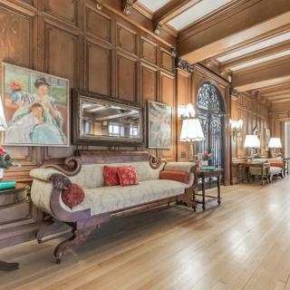 A luxurious vintage living room featuring wood paneling, classic furniture, and artwork adorning the walls.