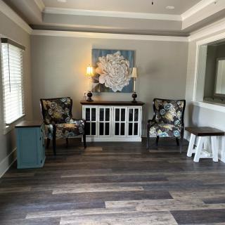A cozy living room with armchairs, a cabinet, and a decorative painting.
