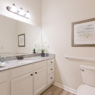 A clean and modern bathroom with a vanity, mirror, and toilet.