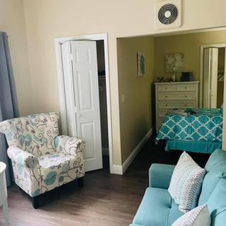A cozy living space with a blend of a bedroom and sitting area featuring floral armchairs and a teal sofa.
