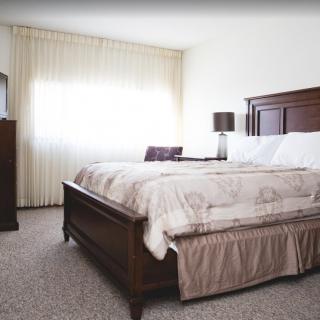 A cozy bedroom with a large bed, wooden furniture, and soft natural lighting.