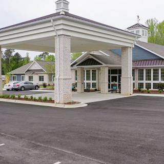 A view of a building entrance with a canopy and nearby parking lot.