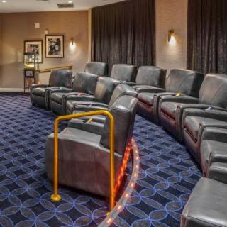 Luxury theater seating with recliners and a handrail for accessibility.