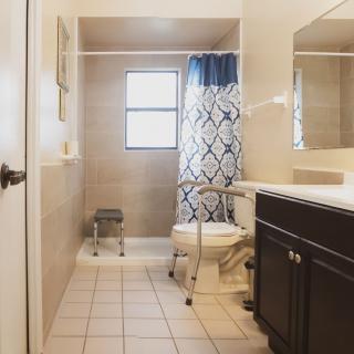 A well-lit bathroom with a shower, toilet, and vanity.