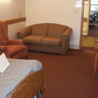 A cozy living room with a brown sofa, an armchair, and carpeted flooring.
