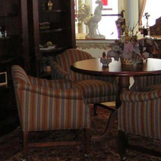 A cozy living room setting with striped chairs surrounding a wooden table.
