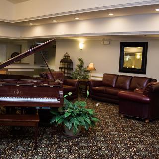A cozy living room with a grand piano and leather sofas.