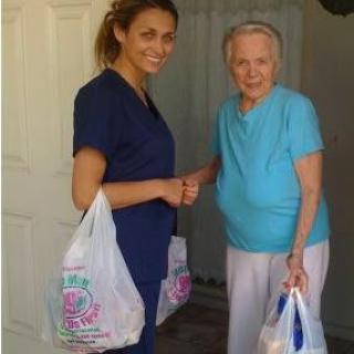 A caregiver assisting an elderly woman with groceries at her home.