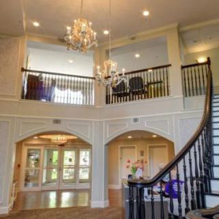A spacious and elegant living area featuring a grand staircase and a chandelier.