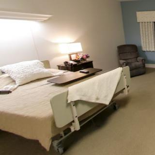 A hospital room featuring a bed and a side table with a lamp, creating a comfortable environment.