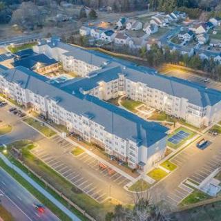 An aerial view of a well-lit apartment complex in a suburban neighborhood during the evening.
