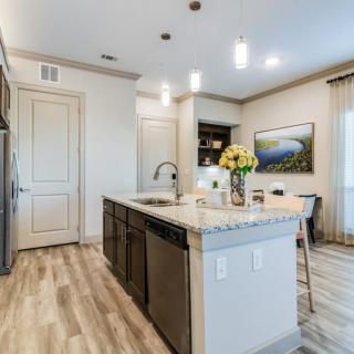 A modern kitchen interior featuring an island with a wooden floor and stylish lighting.