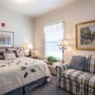 A cozy bedroom with a bed, sofa, and soft lighting.