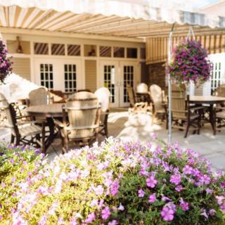 A sunny outdoor patio at a restaurant with tables, chairs, and vibrant flowers.