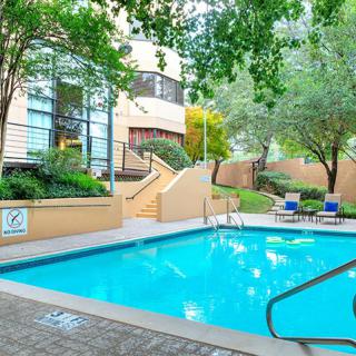 A serene outdoor swimming pool area surrounded by greenery at an apartment complex.