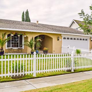 Suburban house with a white picket fence and well-manicured lawn.