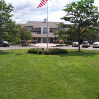 A building with an American flag, surrounded by trees and a well-maintained lawn.