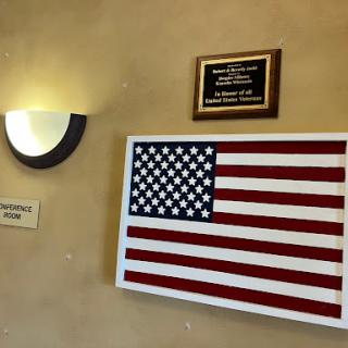 An American flag displayed on a wall alongside a plaque, representing patriotism and national pride.