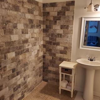 A stylish bathroom featuring a tiled wall, pedestal sink, and framed mirror.