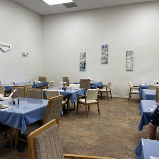 A spacious and inviting dining area featuring neatly arranged tables with blue tablecloths.