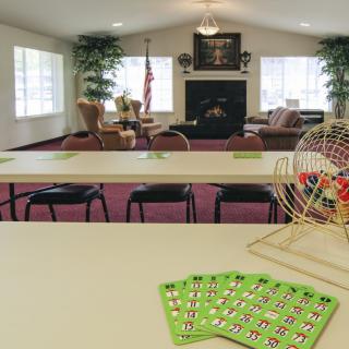 A community game room set up for a bingo session with cards and a bingo cage on the table.