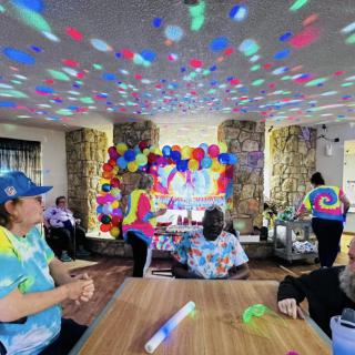 A lively indoor party with colorful tie-dye shirts and vibrant decorations.