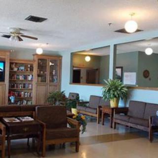 A cozy waiting room with comfortable seating, bookshelves, and indoor plants.