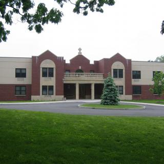 A front view of a school building with a manicured lawn and trees.