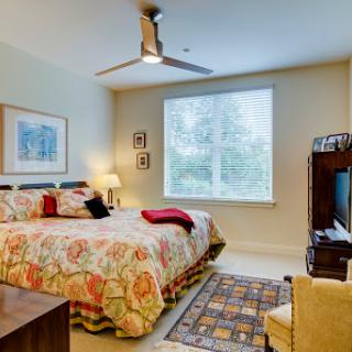 A cozy and inviting bedroom featuring colorful bedding, a window with natural light, and modern dcor.
