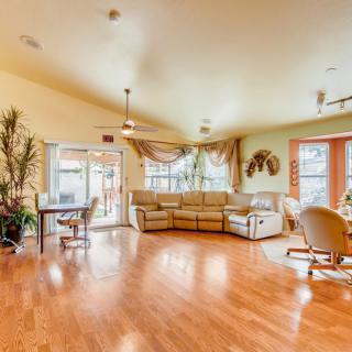 A spacious living room with hardwood floors, a large sofa, and a dining area near the windows.