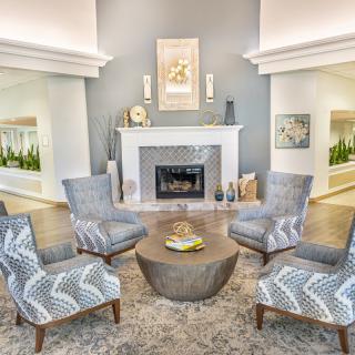 A modern living room featuring a central fireplace, surrounded by patterned chairs and a round wooden table.