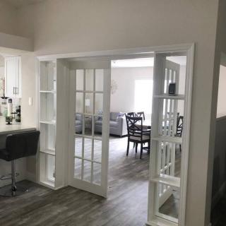 A modern living space featuring an open floor plan with French doors leading to a dining area.
