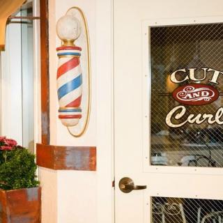 A barbershop entrance with a classic barber pole and decorative signage on the door.